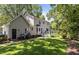 View of the back of the home, featuring a well-maintained lawn, patio, deck, and mature trees at 7517 Chippenham Ct, Raleigh, NC 27613