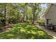 Large backyard with green grass, mature trees, a playground set, and a paved patio area with grill at 7517 Chippenham Ct, Raleigh, NC 27613
