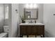 Bathroom vanity with dark wood cabinets, white countertop, framed mirror, and modern fixtures at 7517 Chippenham Ct, Raleigh, NC 27613