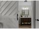 Bathroom featuring dark wood vanity with white countertop, framed mirror, and sliding barn door entrance at 7517 Chippenham Ct, Raleigh, NC 27613