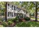 Two-story home with light siding, black shutters, brick chimney, landscaped front yard, and inviting front porch at 7517 Chippenham Ct, Raleigh, NC 27613