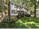 Two-story home with light siding, black shutters, brick chimney, and a well-manicured lawn with trees and flower beds at 7517 Chippenham Ct, Raleigh, NC 27613