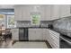 Stylish kitchen with white cabinetry, black countertops, and decorative backsplash, ready for cooking at 7517 Chippenham Ct, Raleigh, NC 27613