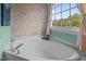 Bright bathroom featuring a relaxing tub with stone accent wall and a window with natural light at 7621 Troy Stone Dr, Fuquay Varina, NC 27526