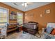 Bedroom with a dark wood crib, colorful rug, and window letting in natural light at 7621 Troy Stone Dr, Fuquay Varina, NC 27526