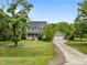 View of the home with a detached garage and an expansive green lawn with mature trees under a blue sky at 7621 Troy Stone Dr, Fuquay Varina, NC 27526
