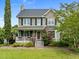 Charming two-story home featuring a welcoming front porch with black shutters and lush landscaping at 7621 Troy Stone Dr, Fuquay Varina, NC 27526