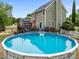 Backyard view of an above ground pool with a deck and a charming two-story home with landscaped yard at 7621 Troy Stone Dr, Fuquay Varina, NC 27526
