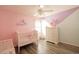 Pink and lavender accent walls, crib, and dresser with a ceiling fan in a bedroom at 780 Pondview Ct, Rocky Mount, NC 27804