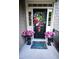 Inviting front door adorned with flowers, a wreath, and a colorful welcome mat, creating a warm entrance at 82 Idlewood Ln, Clayton, NC 27527