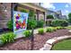 Charming front yard featuring a welcome flag, blooming plants, and decorative stone edging at 82 Idlewood Ln, Clayton, NC 27527