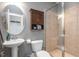 Bright bathroom with a pedestal sink, tiled shower, and built-in cabinet for storage at 821 Laurel Garden Way, Cary, NC 27513