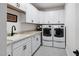 Functional laundry room with white cabinetry, granite countertops, a sink, and modern washer and dryer units at 901 Del Webb Manor Ave, Wake Forest, NC 27587