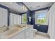 Bright bathroom with dual sinks, white cabinets, and a large window overlooking a lush yard at 1004 Taywood Way, Apex, NC 27502