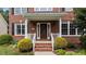 Charming brick home featuring a covered front porch, manicured shrubs, and a stylish front door at 1004 Taywood Way, Apex, NC 27502