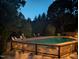Outdoor swimming pool with a wooden deck featuring string lights and manicured landscaping at 1004 Taywood Way, Apex, NC 27502