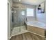 Bathroom boasting glass enclosed shower, soaking tub, wood look flooring, and natural light at 1039 Bellenden Dr, Durham, NC 27713