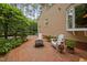 Brick backyard patio featuring garden beds, Adirondack chairs, and lush greenery at 108 Farren Ct, Cary, NC 27511