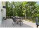 A relaxing back porch features gray deck, black metal railings, chairs and dining table perfect for outdoor entertaining at 10817 Brass Kettle Rd, Raleigh, NC 27614