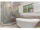 Bright bathroom features a luxurious soaking tub and frameless glass shower near an open window at 1101 Temple St, Raleigh, NC 27609