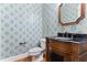 Charming powder room with patterned wallpaper, wooden vanity, black countertop, and decorative mirror at 1101 Temple St, Raleigh, NC 27609