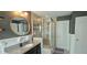 Modern bathroom with a glass-enclosed shower, granite countertop vanity, and round mirror at 1116 Trotter Bluffs Dr, Holly Springs, NC 27540