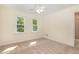 Comfortable bedroom featuring a ceiling fan, two windows, neutral carpet, and access to bathroom at 122 N Fern Abbey Ln, Cary, NC 27518