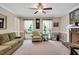 Spacious living room with a ceiling fan, two large windows, and a cozy sitting area near a brick fireplace at 124 Windmere Dr, Angier, NC 27501