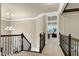 Hallway with wrought iron banister and chandelier leads to another room with an exercise machine at 1540 Sandybrook Ln, Wake Forest, NC 27587
