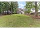 Large backyard with a wooden deck and ample green space surrounded by mature trees at 1605 Hall Blvd, Garner, NC 27529