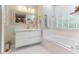 Bright bathroom features a white vanity, tiled bathtub, and a large mirror that enhances the spacious feel at 1605 Hall Blvd, Garner, NC 27529