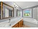 Bright bathroom featuring double sinks, a soaking tub, and a window offering natural light at 1605 Old London Way, Apex, NC 27523