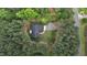 Aerial view showcases a home with dark roof nestled within lush greenery and surrounded by mature trees at 1850 Willie Pace Rd, Burlington, NC 27217