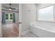 A bathroom with a bathtub, wood flooring, blue curtains and a window with lots of natural light at 1850 Willie Pace Rd, Burlington, NC 27217