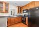 Well-lit kitchen featuring wooden cabinets, a black refrigerator, and modern appliances at 2111 Piney Brook Rd # 101, Raleigh, NC 27614