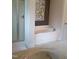 Bright bathroom with soaking tub, shower and neutral-toned walls and stylish botanical art at 243 Nortwick Rd, Rolesville, NC 27571