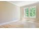Bright, empty bedroom with hardwood floors and large windows overlooking nature at 2737 Willow Rock Ln, Apex, NC 27523