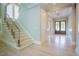 Bright foyer featuring hardwood floors, a staircase with glass railings, and a view of the front doors at 2737 Willow Rock Ln, Apex, NC 27523