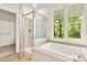 Bathroom featuring a luxurious soaking tub, a separate shower, and a large window with a view of the outdoors at 2819 Ellis Chapel Rd, Bahama, NC 27503