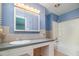 Bathroom with a blue accent wall, large vanity, and a bathtub featuring tile wall accents at 3125 Stanford Dr, Durham, NC 27707