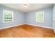 Bedroom features hardwood floors, neutral paint, and two windows, offering potential for customization at 3125 Stanford Dr, Durham, NC 27707