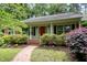 Charming single-story home featuring a welcoming red front door, lush landscaping, and brick pathway to the front porch at 3125 Stanford Dr, Durham, NC 27707
