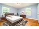 Comfortable bedroom featuring a bed with a padded headboard, two windows and wood floors at 3125 Stanford Dr, Durham, NC 27707