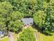 An aerial view showcases a charming house surrounded by lush trees in a serene setting at 324 Waterside Dr, Sanford, NC 27330