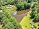 An aerial shot shows a tranquil pond surrounded by lush greenery, with scattered buildings and sheds at 324 Waterside Dr, Sanford, NC 27330