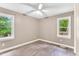 Bright bedroom with modern ceiling fan, two windows, and beautiful gray laminate flooring at 324 Waterside Dr, Sanford, NC 27330