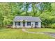 Charming single-story home featuring a well-manicured lawn, walkway, and inviting front porch, framed by lush trees at 324 Waterside Dr, Sanford, NC 27330