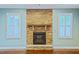 Close-up of the stone fireplace with a wooden mantle and hearth, flanked by bright, shuttered windows at 337 Shadowdale Ln, Rolesville, NC 27571