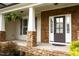 Inviting covered front porch featuring stone pillars, brick accents, and hanging ferns offering great curb appeal at 337 Shadowdale Ln, Rolesville, NC 27571