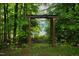 Lush backyard featuring a wooden archway framing a view of the lake between the trees at 3750 Mebane Rogers Rd, Mebane, NC 27302